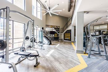 a spacious fitness center with cardio equipment and a spiral staircase